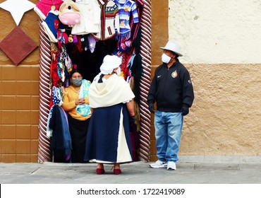 Cuenca, Ecuador - April 23, 2020: Indigenous People Of Ecuador From Otavalo - Buyers And Seller Woman All Of Them In Masks Next To The Small Cloth Store During COVID-19 Pandemic