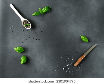 Culinary background. Basil, black pepper and kitchen knife on black background. Copy space for text