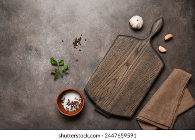 Culinary background with empty wooden cutting board, spices and garlic, dark brown rustic table. Top view, flat lay, copy space. - Powered by Shutterstock