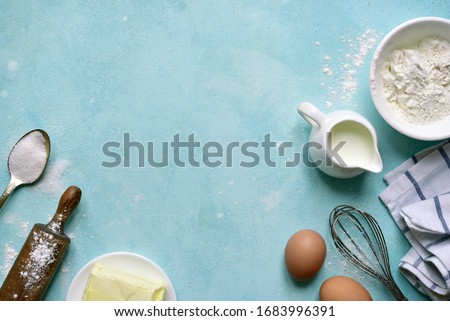 Culinary background with ingredients for baking : flour, butter, eggs, milk and sugar on a light blue slate, stone or concrete table. Top view with copy space.