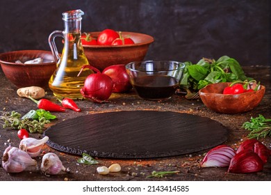 Culinary background with kitchen slate round board, olive oil in a jug and vegetables. Empty space for menu or recipe with selective focus - Shutterstock ID 2143414585