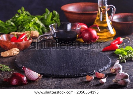 Culinary background with kitchen slate stone serving platter, olive oil and vegetables. Selective focus with copy space for text