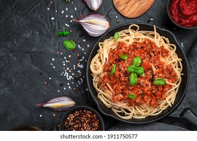 Culinary background with pasta and tomato sauce and fresh herbs on a black concrete background. The concept of cooking.