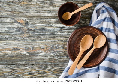 Culinary Background With Rustic Kitchenware: Ceramic Plates, Wooden Or Bamboo Spoons And Towel On Vintage Wooden Background. Rustic Style. Home Kitchen Decor. View From Above.