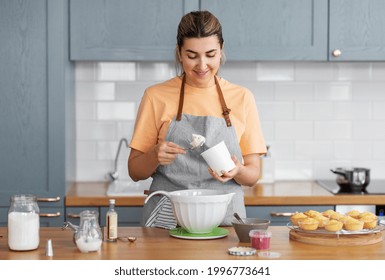 Culinary, Baking And People Concept - Happy Smiling Young Woman Cooking Food On Kitchen At Home With Cupcakes Making Topping Of Whipped Cream Or Mascarpone Cheese