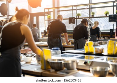 Culinary class. Back view of the process of cooking. Different unrecognizable people in gray aprons the in the kitchen learn to cook. Cooking workshop. cook training - Powered by Shutterstock