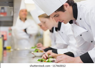 Culinary Class In Kitchen Making Salads As Teacher Is Overlooking