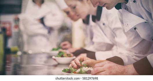 Culinary class in kitchen making salads as teacher is overlooking - Shutterstock ID 581297698