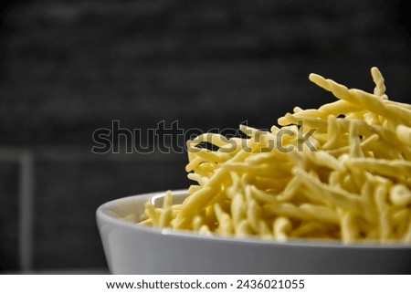 Culinary Elegance Unveiled: A Captivating Close-Up of a Brimming Bowl of Raw Trofie Pasta, Poised for Transformation in the Culinary Alchemy of Cooking