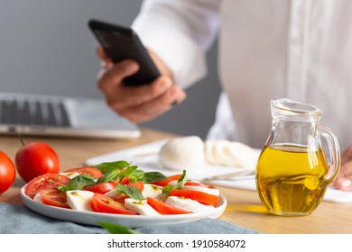 Culinary master class. Man searching information on internet how to cook caprese salad, is Italian famous salad with fresh tomatoes, mozzarella cheese and basil. Virtual master class