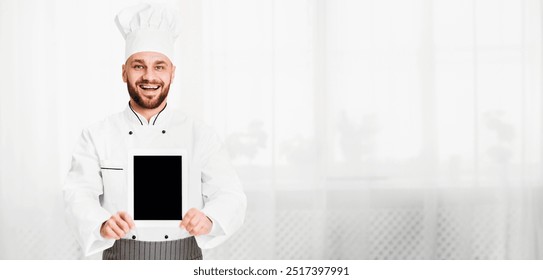 Culinary Recipes App. Chef Cook Man Holding Blank Digital Tablet Screen With Menu Standing In Restaurant Kitchen Indoor. Mockup - Powered by Shutterstock