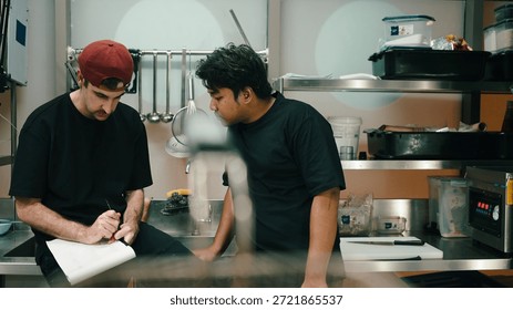Culinary staff working in dark kitchen, discussing orders and workflow
