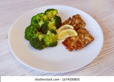 culinary still life baked fish green cabbage broccoli yellow lemon on a white plate