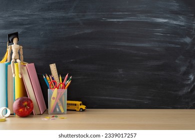 Cultivate love for learning with school-themed setup: side view of desk essentials, stationery stand, books, mannequin in graduate cap on chalkboard backdrop, creating compelling space for text or ad - Powered by Shutterstock