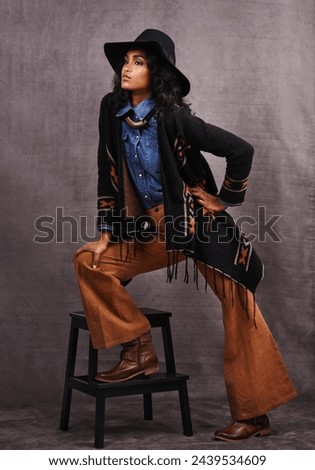 Culture, cowgirl or woman thinking in studio, wild west and cool fashion or clothing on grey background. Native American person, western lady and stylish model with pride, boho style and chair stool