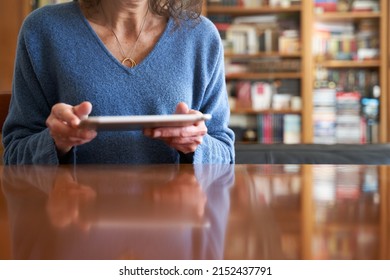 Cultured Senior Woman With Huge Library Reading On Tablet