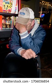 CUMBERLAND, WISCONSIN / USA - OCTOBER 29, 2017: Man At The Bar With Head Down Sitting By A Pin Ball Machine. 