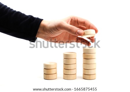 cumulative effect concept on white background. hand builds a pyramid of wooden parts