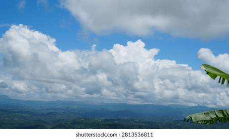 Cumulus clouds and mountain range under a bright blue sky