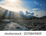 Cumulus clouds over the autumn colorful forest. Mountain landscape. Autumn mountains over the valley of the mountain river. A pleasant azure color of the sky in the distance. Sunbeams among the clouds