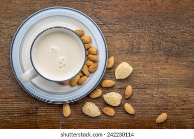 A Cup Of Almond Milk With Almond Nuts On A Rustic Barn Wood Table