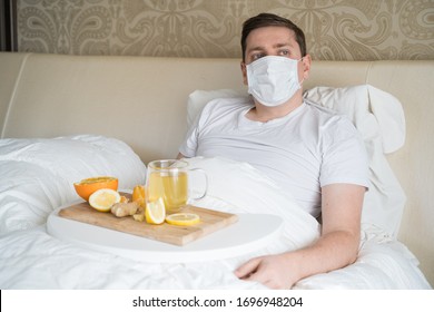 Cup With Antipyretic Drugs For Colds,flu.Sick Man In Bed. Tea With Citrus Vitamin C,ginger Root,lemon,orange.Wooden Tray. Home Self-treatment.Medical Quarantine Antiviral Covid-19 Coronavirus Therapy.