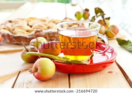 Cup of apple tea on a red plate
