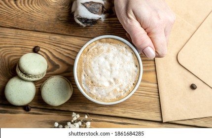 Cup of aromatic coffee and macaroons and an envelope on a wooden table. Concept of a cozy atmosphere and nice breakfast.