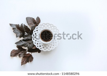 A cup of aromatic espresso or black tea. Nearby lie autumn leaves. Simple minimalistic autumn design.