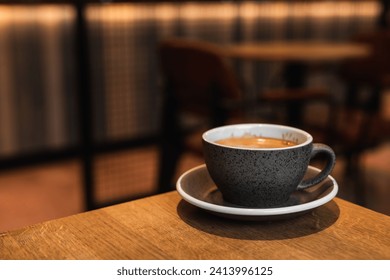 Cup of black coffee on saucer standing on the edge of a wooden table in a cafe coffee-shop with copy space - Powered by Shutterstock