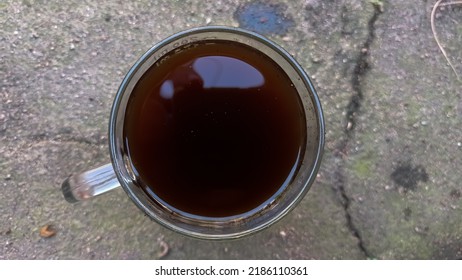 A Cup Of Black Coffee Is Placed On The Sandy Floor
