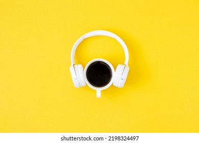 A cup of black coffee and white headphones on yellow background. Minimal style, Flat lay, Top view. Education concept.