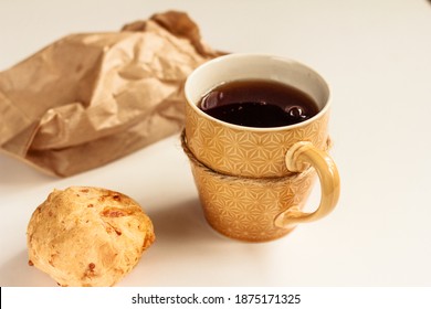 Cup Of Black Tea, Cheese Roll, A Brown Kraft Paper Bag On White Background. Isolated.  Snack Time. Stock Photo