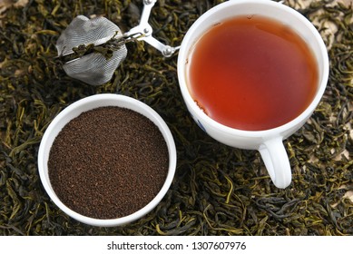 Cup Of Black Tea And Heap Of Dried Organic Tea Leaves, Dust And Infuser  Munnar, Kerala, India. Aromatic Herbal Indian Beverage For Relaxation, Stress Relief. Healthy Drink Has Antioxidants, Nutrients