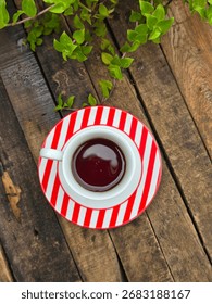 Cup of Black Tea on Rustic Wooden Table with Green Leaves
