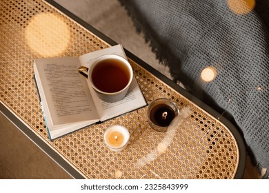 Cup of black tea stay on open paper book with scented candles on rattan table in living room top view. Selective focus. Good morning.  - Powered by Shutterstock