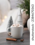 cup of cacao with marshmellows, christmas tree on coffee table on white pillow background.