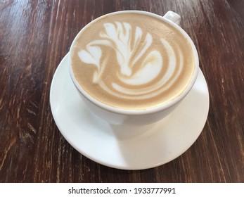 A cup of caffe latte with latte art on surface.