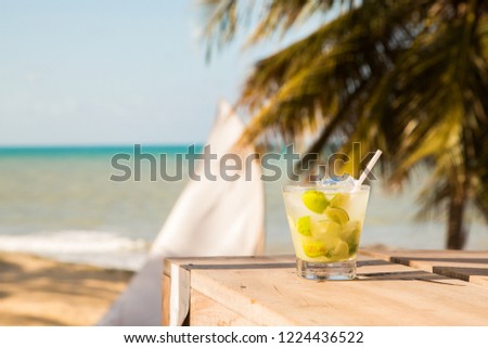 Cup of caipirinha with Brazilian beach and coconut trees in the background.
Caipirinha. Northeastern Brazilian beach