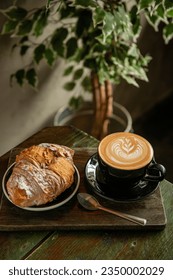 Copa de Cappuccino con bello arte de latte crema con una pastelería en una mesa de café. Fondo de madera.
