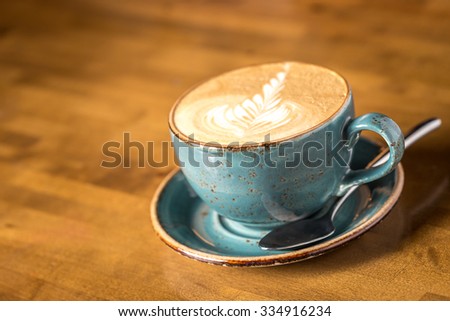 Cup of cappuccino coffee isolated on wooden background