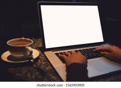 A cup of cappuccino coffee with laptop white screen on table. Royalty high quality free stock photo image of coffee cup with laptop for working in a coffee shop, typing with blank screen white color