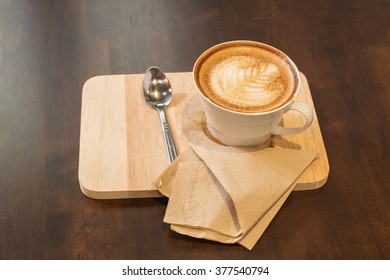 Cup of cappuccino coffee on wooden background.
