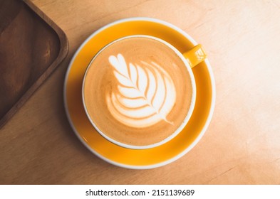 Cup of cappuccino coffee with Rosetta latte art stands on a wooden desk, top view - Powered by Shutterstock