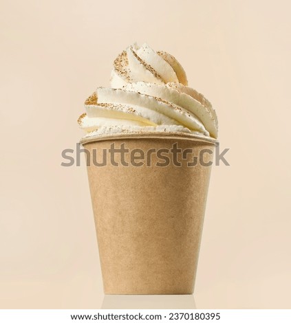 cup of cappuccino decorated with whipped cream and cinnamon on beige color background
