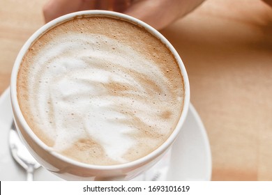Cup of cappuccino in hand, top 10 photos, coffee in hand, foam drawing on a latte. beige picture with a white cup of coffee