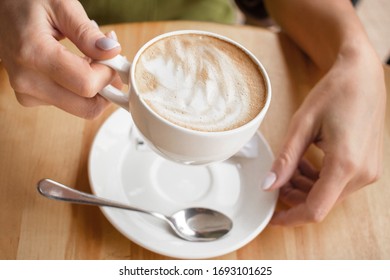 Cup of cappuccino in hand, top 10 photos, coffee in hand, foam drawing on a latte. beige picture with a white cup of coffee