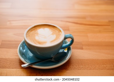 Cup of cappuccino with latte art. Coffee in blue cup on wooden table in cafe - Shutterstock ID 2045048102