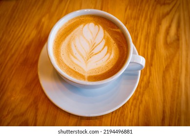 Cup Of Cappuccino Latte Art On A Amber Wood Table.