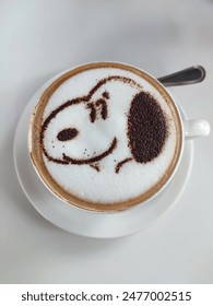 A cup of cappuccino with Snoopy's face in white table